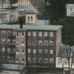 Colorized early 20th century postcard showing brick and wooden mill buildings and a few houses.