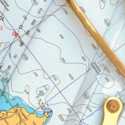 Nautical chart with contour lines and coastal details, overlaid with a pair of brass dividers and a ruler. The image conveys navigation and exploration.