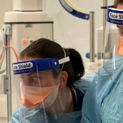 Three clinicians in PPE performing an airway procedure during resuscitation training
