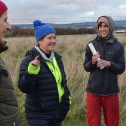 Smiling people dressed warmly and gathered in a group in the fields of Lauriston Farm