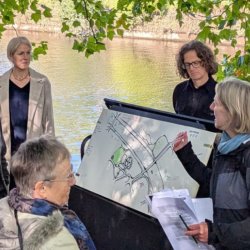 Group gathered beside the river around an illustrated map during a discussion about rivers, communities and environmental resilience.