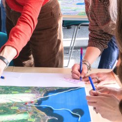 People standing around a map and writing on post-it notes.