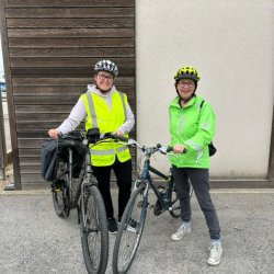Two female cycling instructors in high vis cycle clothing are smiling after training people to ride bikes