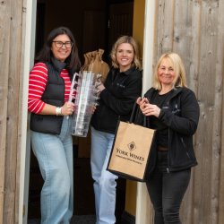 3 team members smile and prepare for a wine tasting event