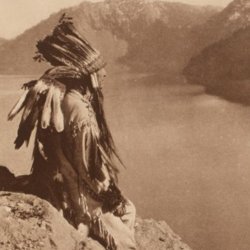 A person in traditional attire sits on a rocky cliff, overlooking a serene lake with mountain peaks in the background. The scene feels contemplative.