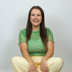 photo of Donna, Hypnobirthing teacher, sat crossed legged with yellow trousers and a green floral top
