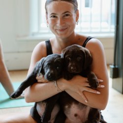 Woman smiling holding puppies in a hug