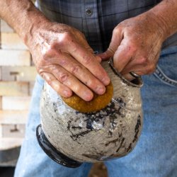 Potter cleaning the outside of newly fired Raku pot
