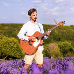 Chard musician standing playing guitar among the lavender