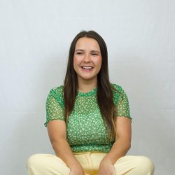 photo of Donna, Hypnobirthing teacher, sat crossed legged with yellow trousers and a green floral top