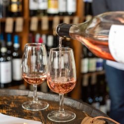 2 glasses of rose wine being poured on a barrel