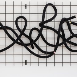 A sculpture that looks like black laces that is fed through a metal grid
