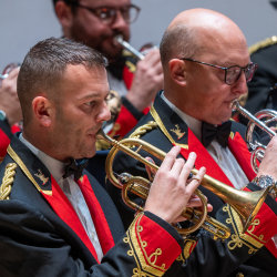 Black Dyke Band cornet and flugelhorn players mid-performance in red-and-gold uniforms.