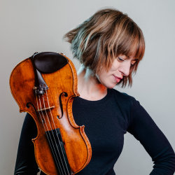 Violinist Fenella Humphreys with her instrument, studio portrait in soft grey light.