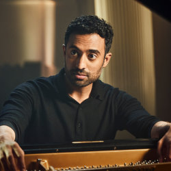 Pianist Cyril Ibrahim at the JAM Festival performing on a Steinway grand in warm low light, looking up from the keys.