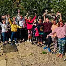 A group of yoga students with hands in the air.