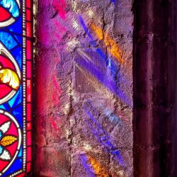 Stained glass reflecting onto stone window frame