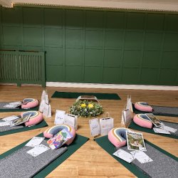 Bump and Chill space set up with 6 Yoga mats and blankets, around a floral display with yellow flowers.