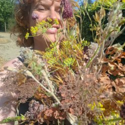 Woman smiling behind large bunch of dried flowers in late summer