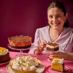 Freya Cox - author of Bake My Day, sitting surrounded by sweet treats and cakes