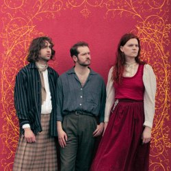 The members of Craven are standing next to each other, looking to the right, in front of a red background with gold ornamentation drawn behind them.