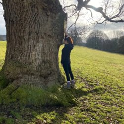 Woman standing beside a large tree during an Autumn wellness workshop with The Wise Womb Woman
