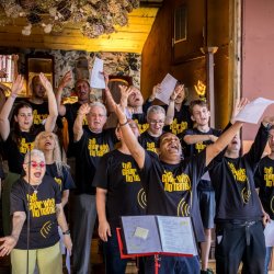 This a picture of CWNN Sheffield at a performance, looking joyful with their arms in the air