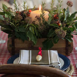 A beautifully styled festive table with antique brick mould packed with seasonal foliage and candle