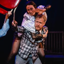 A man reaches forward with another character on his back