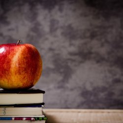 An apple sitting on a pile of books