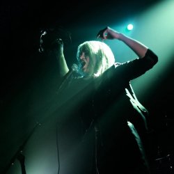 VICE VERA with arms raised, holding a tambourine, singing into a mic