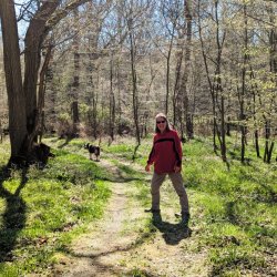 Saltmarsh Coast Walking Festival Winter Walks 2025 - Maureen Bissell featured with dog walking through her private wood. Credit @ Chris Harvey