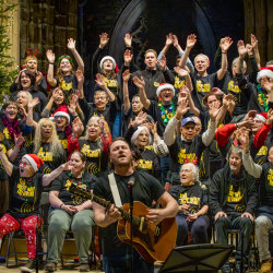 This a picture of CWNN Sheffield performing with Ed Cosen's at last year's Christmas Concert, looking joyful with their arms in the air