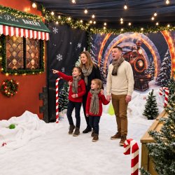 Family exploring Candy Cane Crossing beside the North Pole Bakery and Christmas train backdrop in Gateshead.