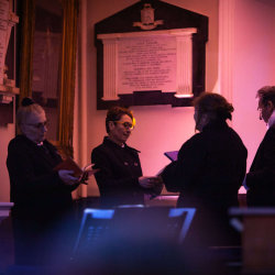 looking up at the domed roof of the Octagon Chapel, bathed in green light. Members of the choir, dressed in black and white, can just be seen in the upper gallery