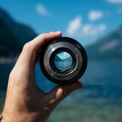 Looking through a camera lense towards a lake surrounded by hills