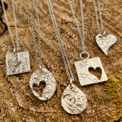 Four Silver Pendants lined up on a wooden background