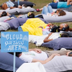 People of all ages and backgrounds lying on beanbags looking at the sky. Sign saying Cloud Gazing Area.