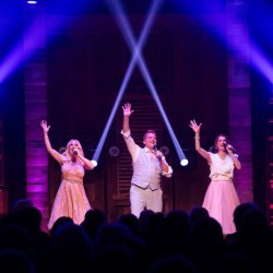 3 singers on stage with colored lights