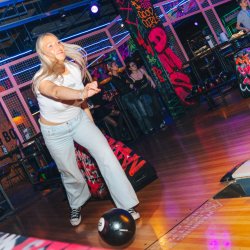 Girl throwing bowling ball down lane
