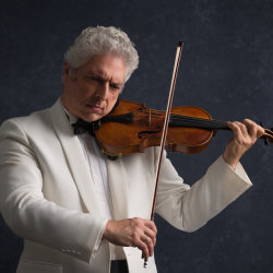 A man in a white suit with white hair plays a violin.