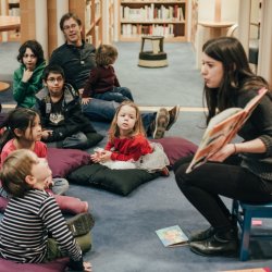 Librarian reading a story to a group of childen.