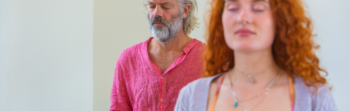 Two peaceful meditators, one a young woman with long red hair, the other an older man with grey swept back hair and beard