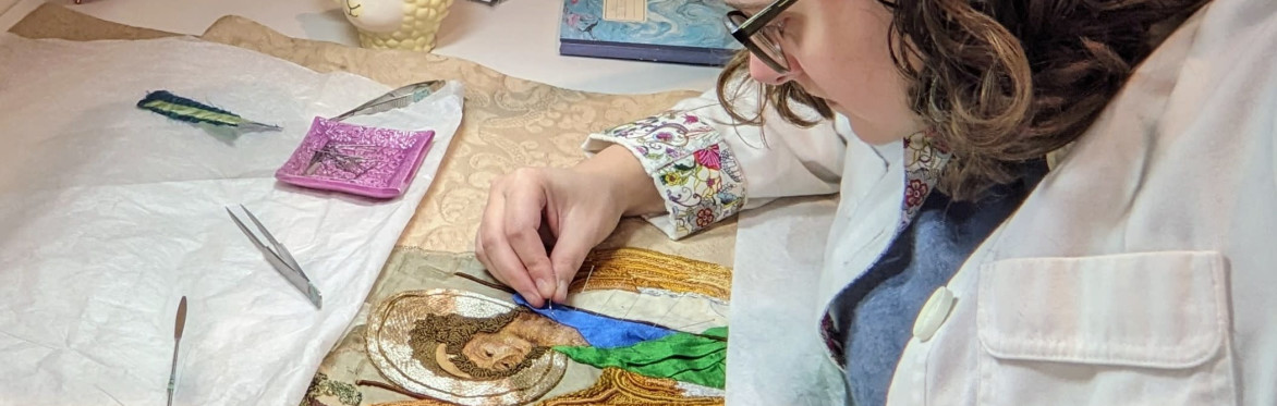 Textile conservator stitching altar cloth with embroidered angels.