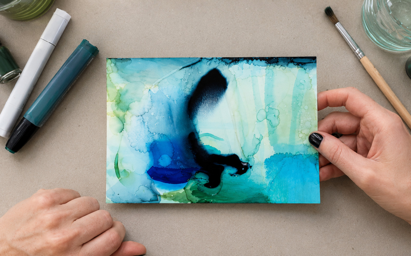 Two participants creating colorful alcohol ink artworks in a bright artist studio.