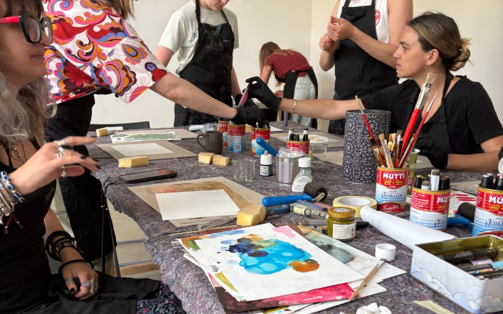 Two participants creating colorful alcohol ink artworks in a bright artist studio.