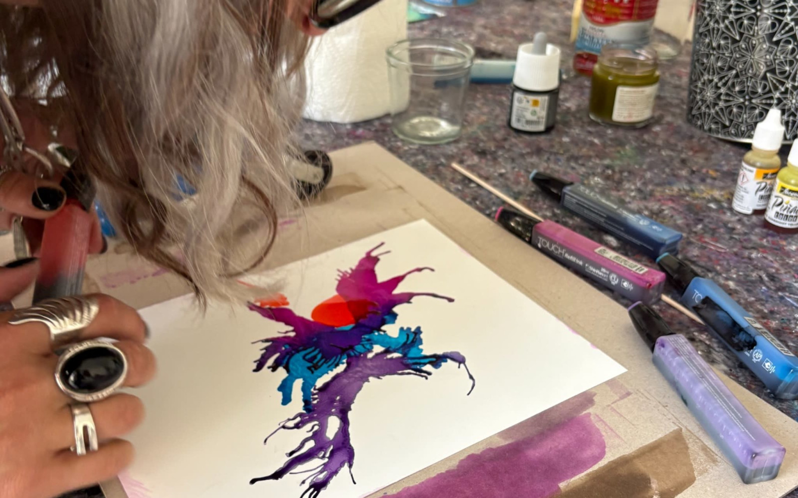 Two participants creating colorful alcohol ink artworks in a bright artist studio.