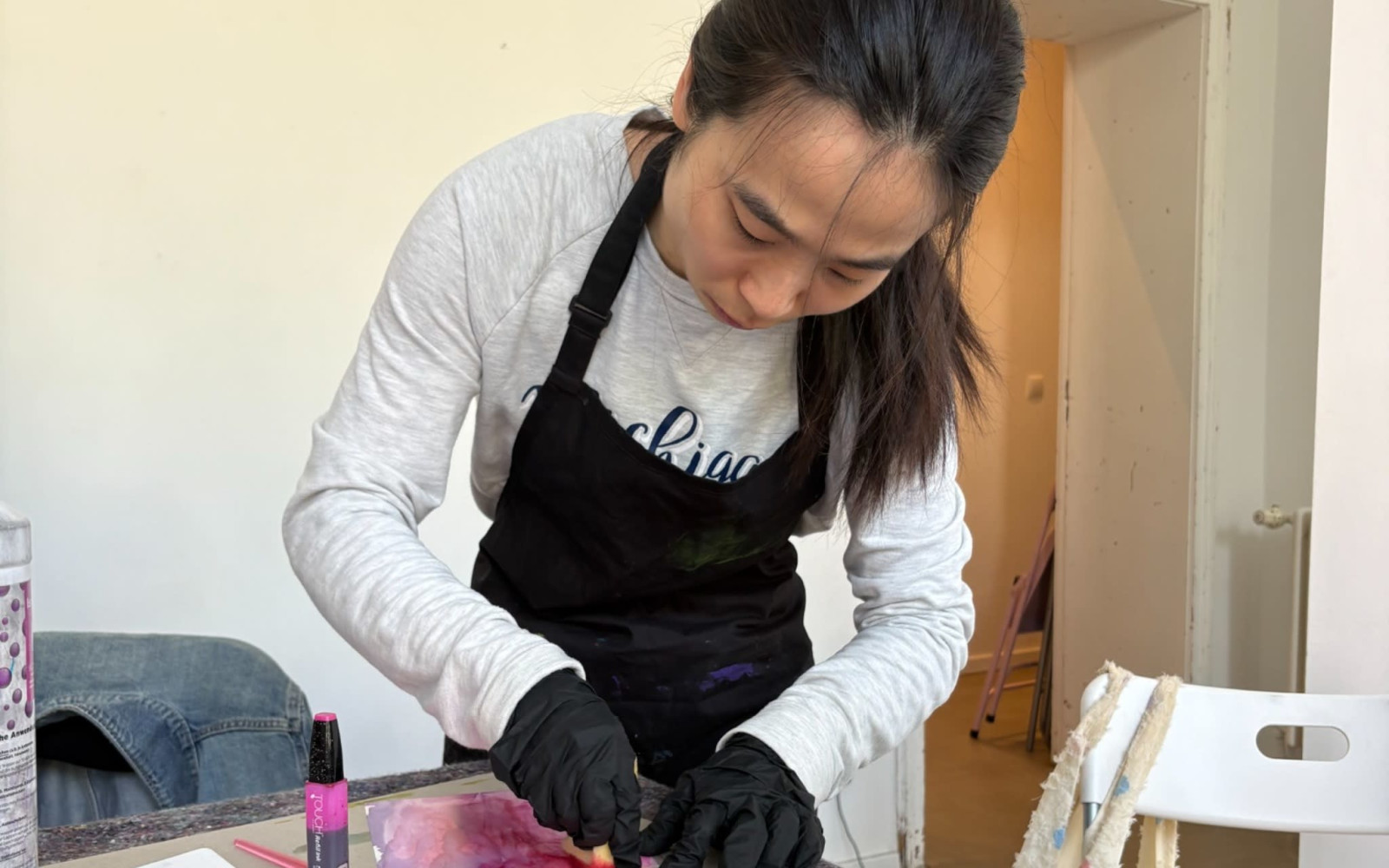 Two participants creating colorful alcohol ink artworks in a bright artist studio.