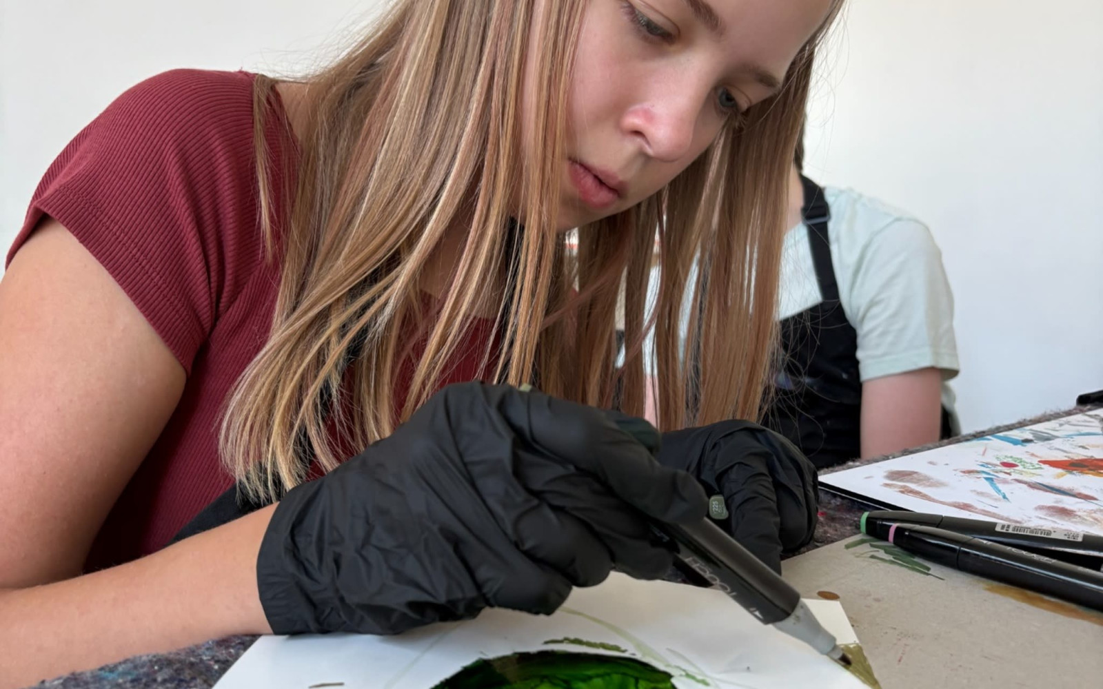 Two participants creating colorful alcohol ink artworks in a bright artist studio.