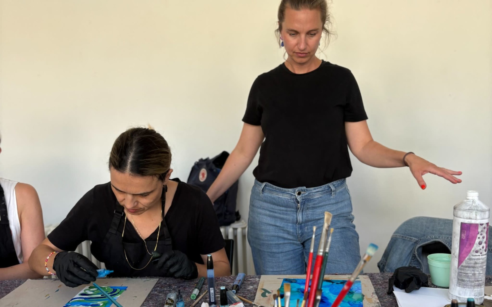 Two participants creating colorful alcohol ink artworks in a bright artist studio.